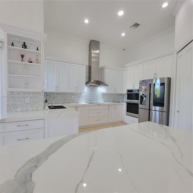 kitchen with visible vents, stainless steel appliances, wall chimney range hood, white cabinetry, and a sink