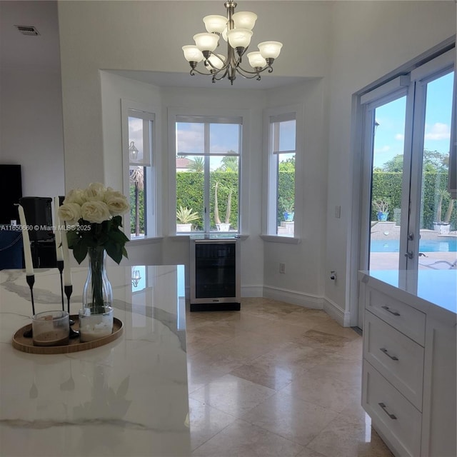 interior space featuring an inviting chandelier, baseboards, wine cooler, and visible vents