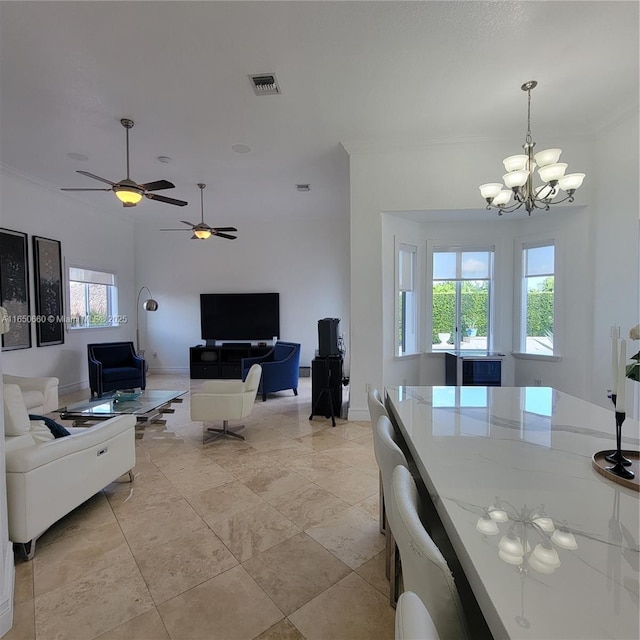 living room with ceiling fan with notable chandelier, ornamental molding, visible vents, and baseboards