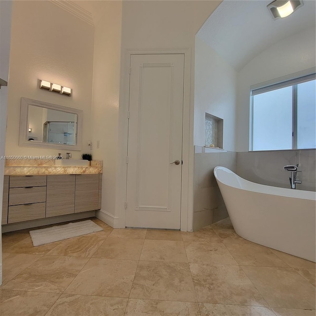 full bathroom featuring a soaking tub, vaulted ceiling, and vanity