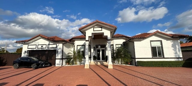 view of front facade featuring decorative driveway, french doors, a tile roof, and stucco siding