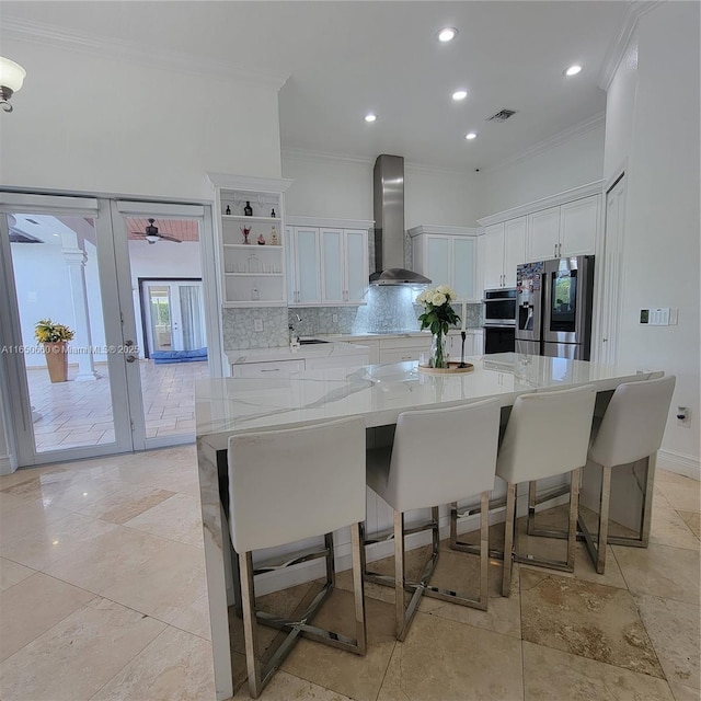 kitchen featuring tasteful backsplash, visible vents, appliances with stainless steel finishes, wall chimney range hood, and white cabinetry