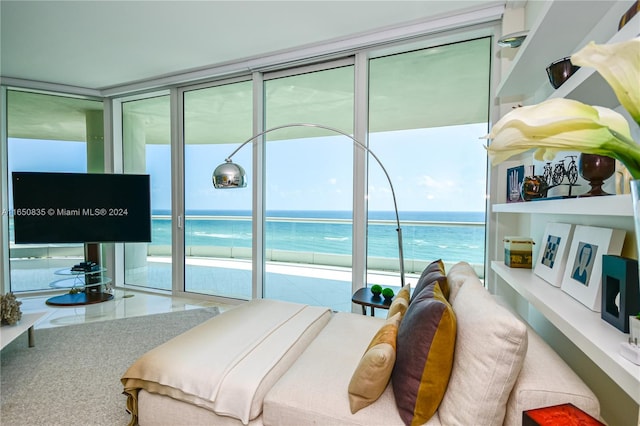 bedroom with access to exterior, expansive windows, and a water view