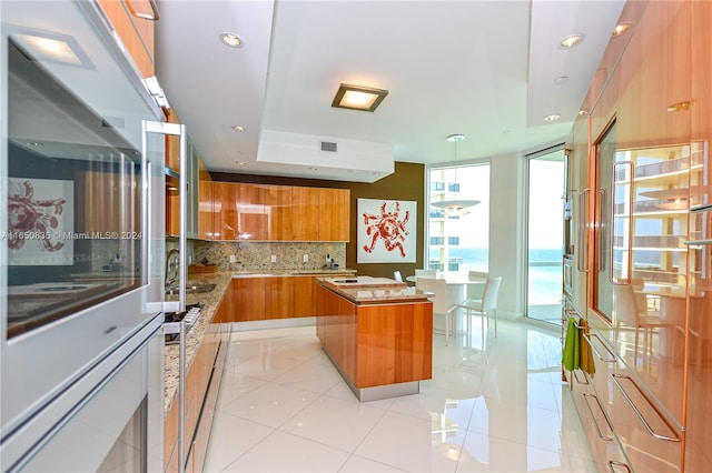 kitchen featuring light tile patterned floors, a kitchen island, tasteful backsplash, and a healthy amount of sunlight