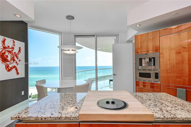 kitchen with a healthy amount of sunlight, light stone counters, and a water view