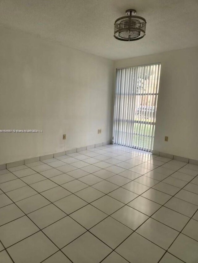 tiled empty room with a textured ceiling