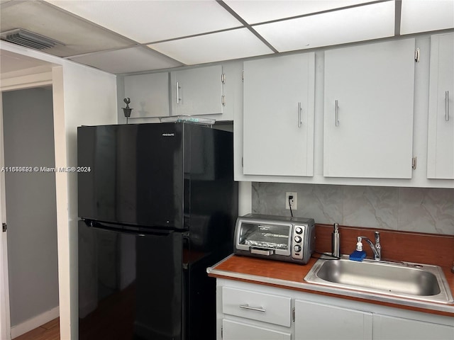 kitchen with a toaster, a sink, visible vents, backsplash, and freestanding refrigerator