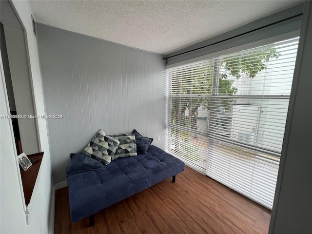 sitting room with wood walls, hardwood / wood-style flooring, and a textured ceiling