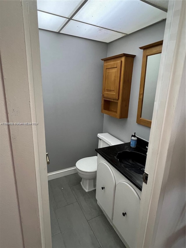 bathroom with vanity, toilet, and a drop ceiling