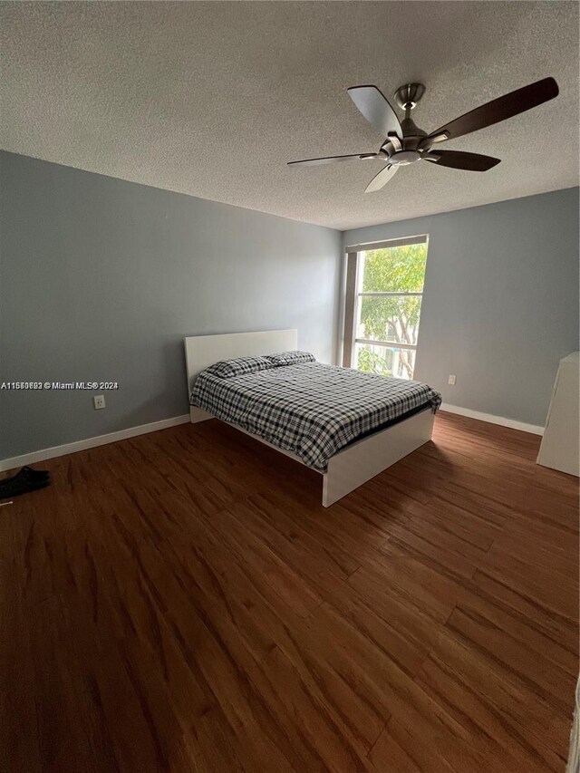 unfurnished bedroom featuring dark wood-type flooring, ceiling fan, and a textured ceiling