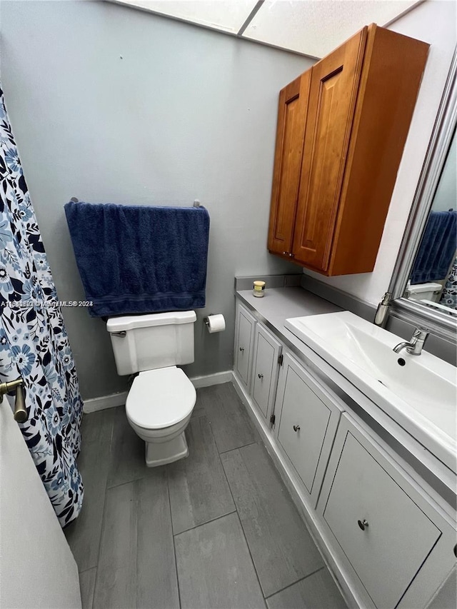 full bathroom with wood tiled floor, baseboards, vanity, and toilet