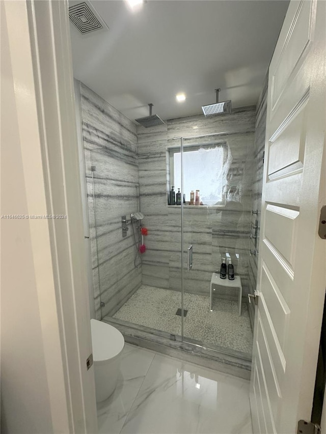 bathroom with a shower with door and toilet