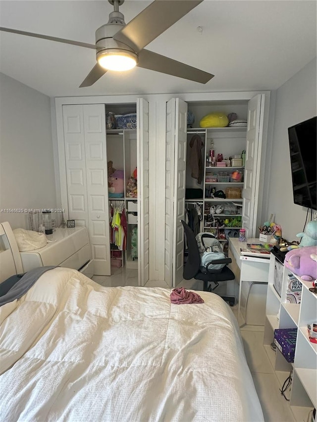 tiled bedroom with multiple closets and ceiling fan