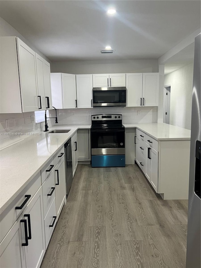 kitchen with light hardwood / wood-style floors, sink, white cabinets, backsplash, and appliances with stainless steel finishes