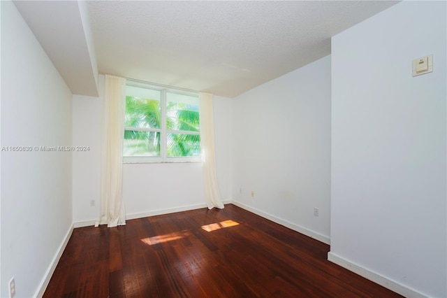 unfurnished room with dark wood-type flooring and a textured ceiling