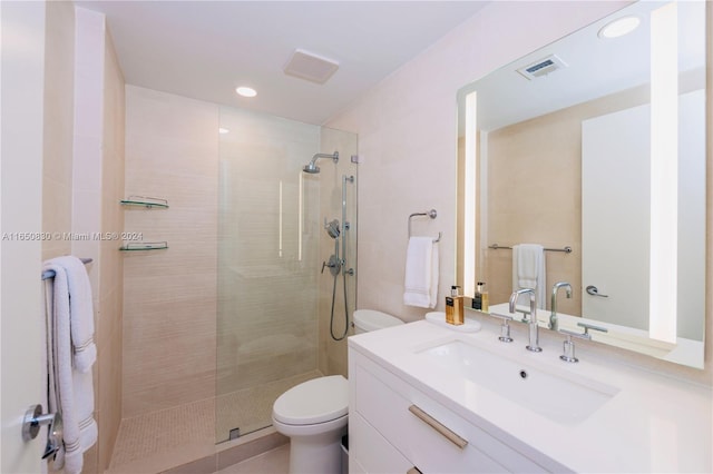 bathroom featuring tiled shower, vanity, and toilet