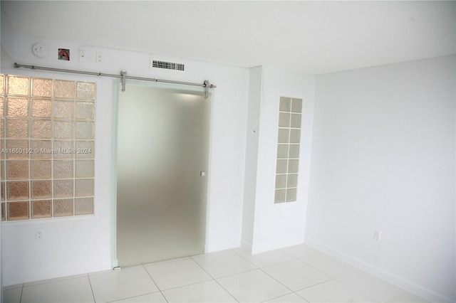 spare room featuring light tile patterned floors and a barn door