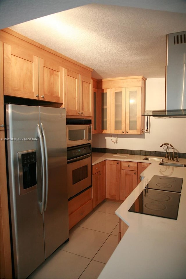 kitchen featuring stainless steel appliances, sink, wall chimney exhaust hood, light tile patterned flooring, and a textured ceiling