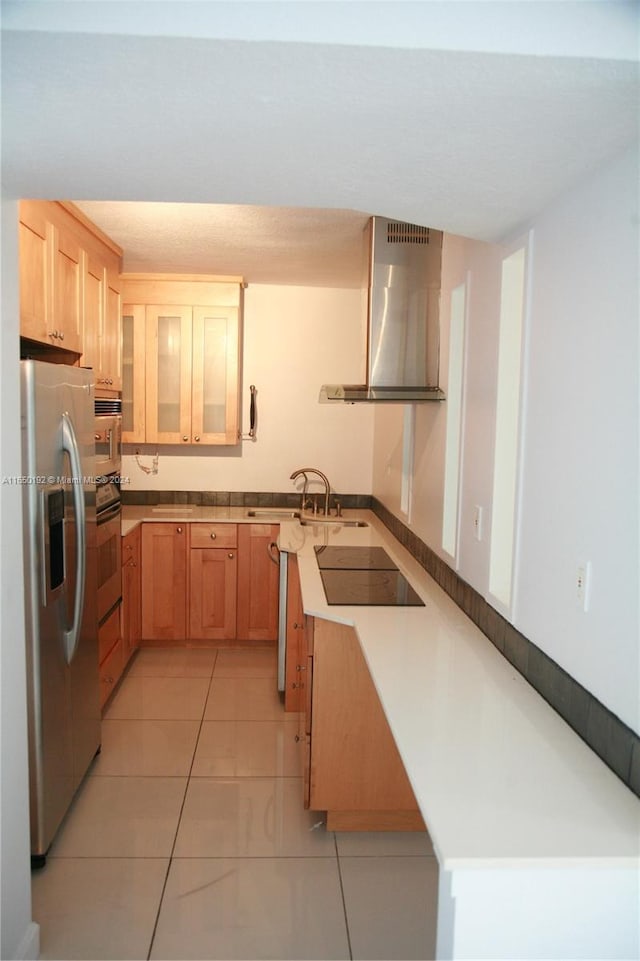 kitchen featuring wall chimney exhaust hood, light tile patterned floors, stainless steel appliances, sink, and kitchen peninsula