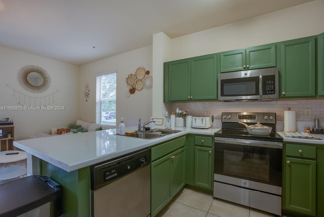 kitchen with green cabinets, kitchen peninsula, stainless steel appliances, and sink