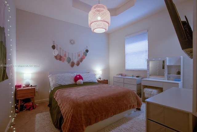 bedroom with light colored carpet and a raised ceiling