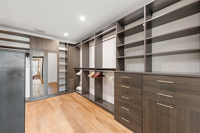 walk in closet with light hardwood / wood-style flooring