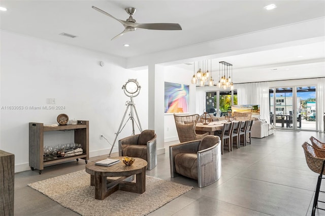 living room with concrete floors and ceiling fan with notable chandelier