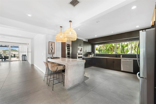 kitchen with appliances with stainless steel finishes, plenty of natural light, tasteful backsplash, and a breakfast bar