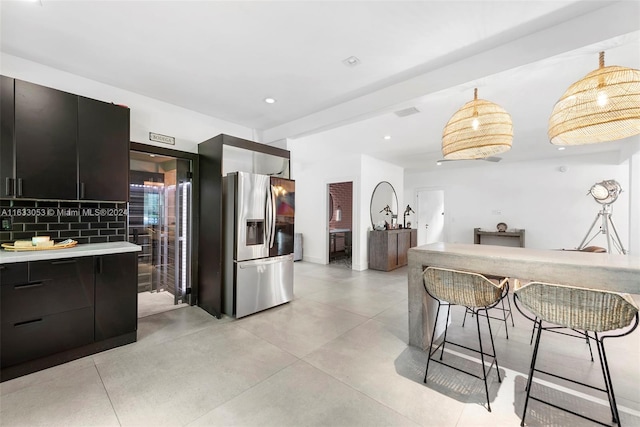 kitchen featuring stainless steel refrigerator with ice dispenser, tasteful backsplash, and decorative light fixtures