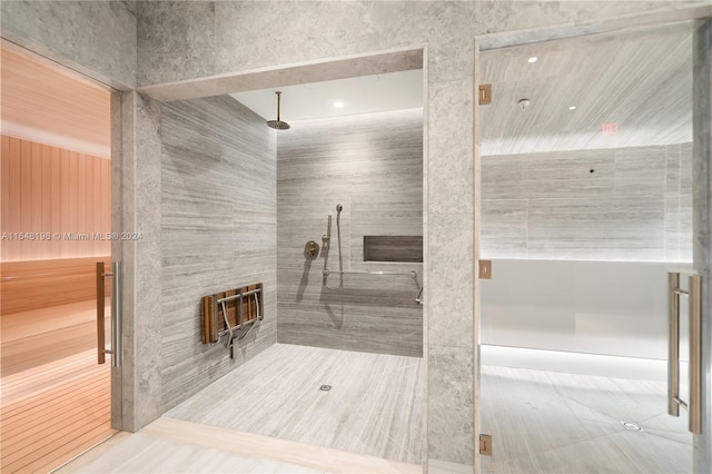 bathroom with a tile shower and tile patterned flooring