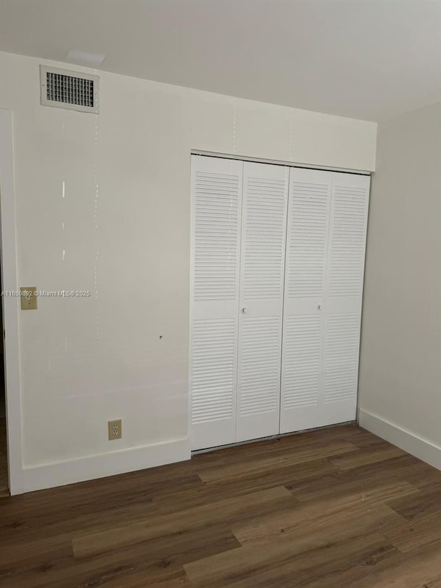 unfurnished bedroom with dark hardwood / wood-style flooring and a closet