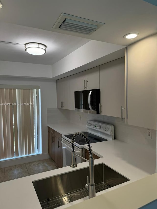 kitchen with sink, white electric range oven, tile patterned floors, and tasteful backsplash