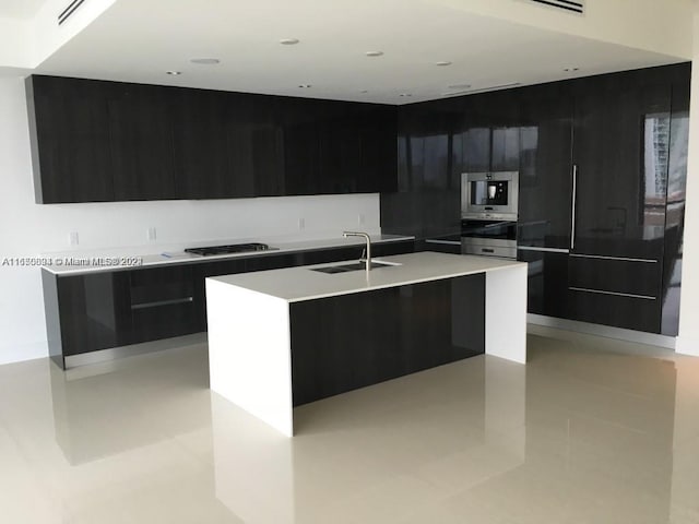 kitchen with a center island with sink, stainless steel gas stovetop, sink, and light tile patterned floors