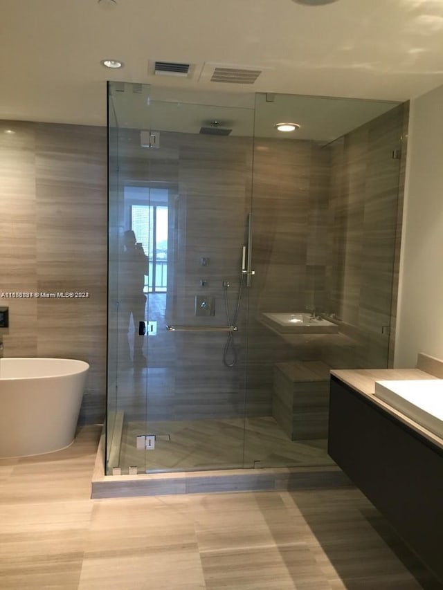 bathroom with vanity, tile walls, and shower with separate bathtub