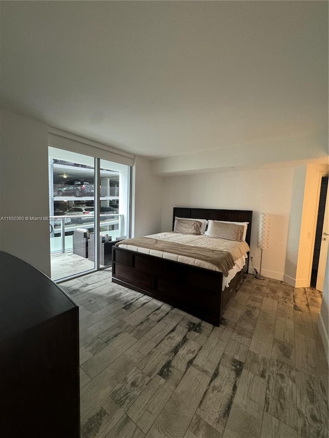 bedroom with access to exterior, light hardwood / wood-style flooring, and expansive windows