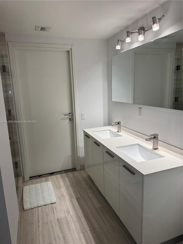 bathroom featuring hardwood / wood-style floors, vanity, and a shower with door