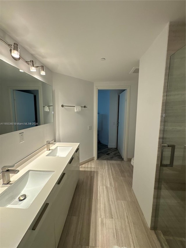 bathroom with vanity, toilet, wood-type flooring, and a shower with door