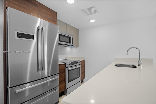 kitchen with stainless steel appliances, light countertops, visible vents, a sink, and modern cabinets