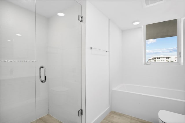 bathroom with a stall shower, visible vents, toilet, and wood finished floors