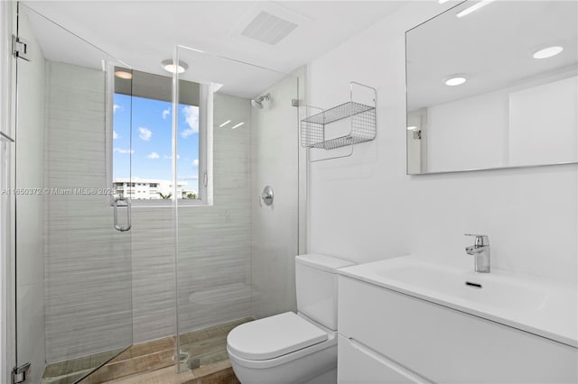 bathroom featuring toilet, a stall shower, vanity, and visible vents