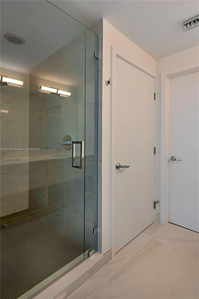 bathroom with a shower with shower door and tile patterned floors