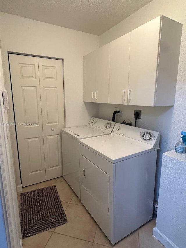 clothes washing area featuring a textured ceiling, cabinets, independent washer and dryer, and light tile patterned floors