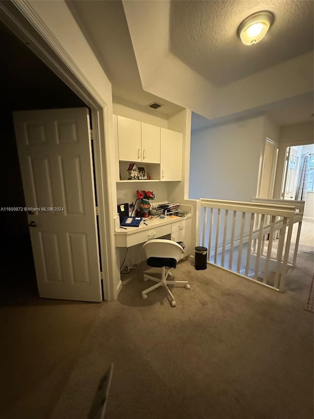 carpeted home office with a textured ceiling