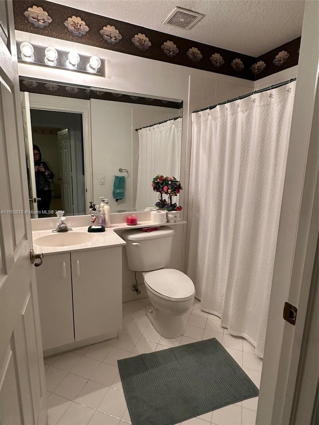 bathroom with a textured ceiling, vanity, a shower with shower curtain, tile patterned flooring, and toilet