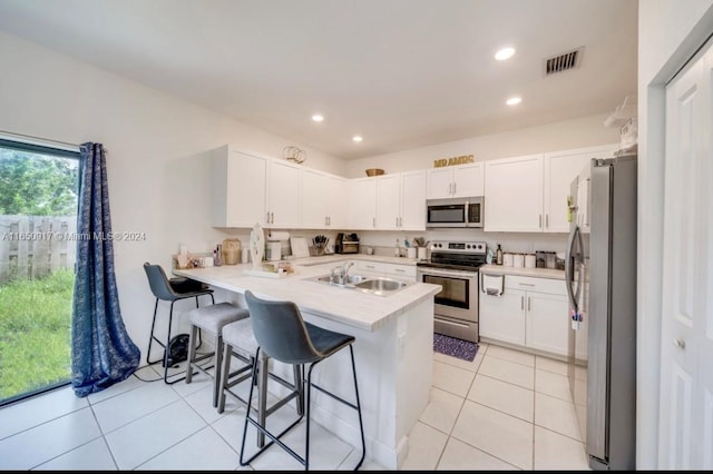 kitchen featuring stainless steel appliances, kitchen peninsula, sink, a breakfast bar, and white cabinets