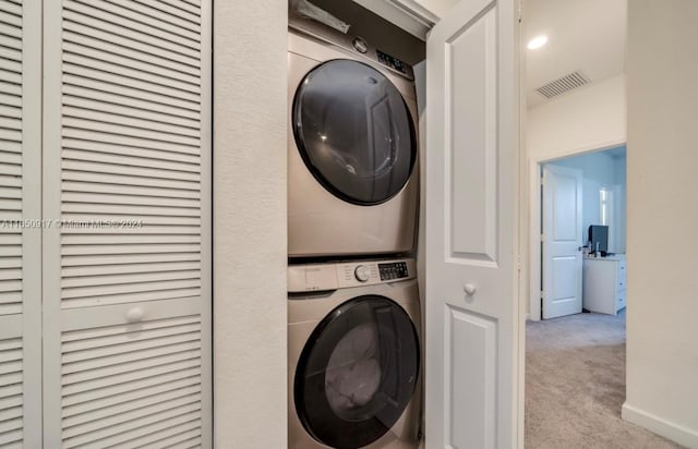 clothes washing area featuring light carpet and stacked washer / drying machine