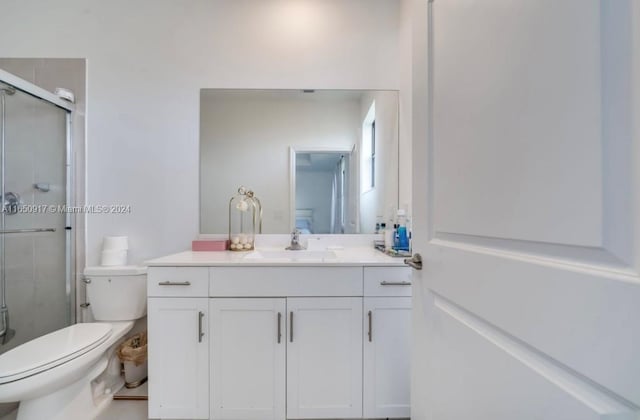 bathroom featuring vanity, toilet, and an enclosed shower