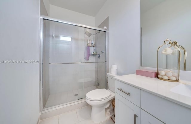 bathroom with vanity, toilet, a shower with shower door, and tile patterned flooring