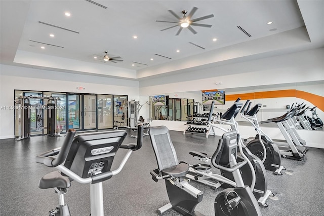 gym featuring a tray ceiling and ceiling fan