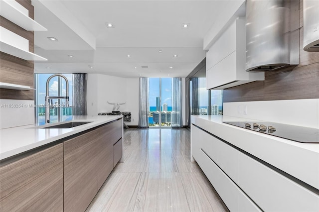 kitchen featuring black electric stovetop, white cabinetry, and sink